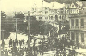 The fire at Parliament buildings on the 11th of December, 1907. Shows a crowd in the foreground and hoses following up through the gate to the Legislative Council steps. Sydney Street West is visible.