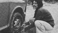Black and white photo showing person at car tyre.
