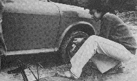 Black and white photo of person changing car tyre.